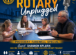 Promotional poster for Grand Rapids Rotary Unplugged featuring a panel at a table with microphones and a city backdrop, including Rotary branding.