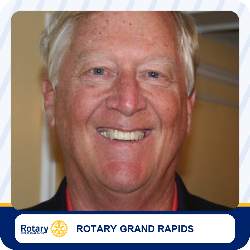 Close-up portrait of a smiling older man in a dark blazer, affiliated with Rotary Grand Rapids.