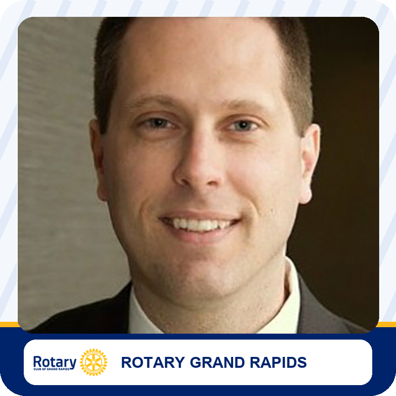 Smiling man in a suit, head-and-shoulders portrait for Rotary Grand Rapids branding